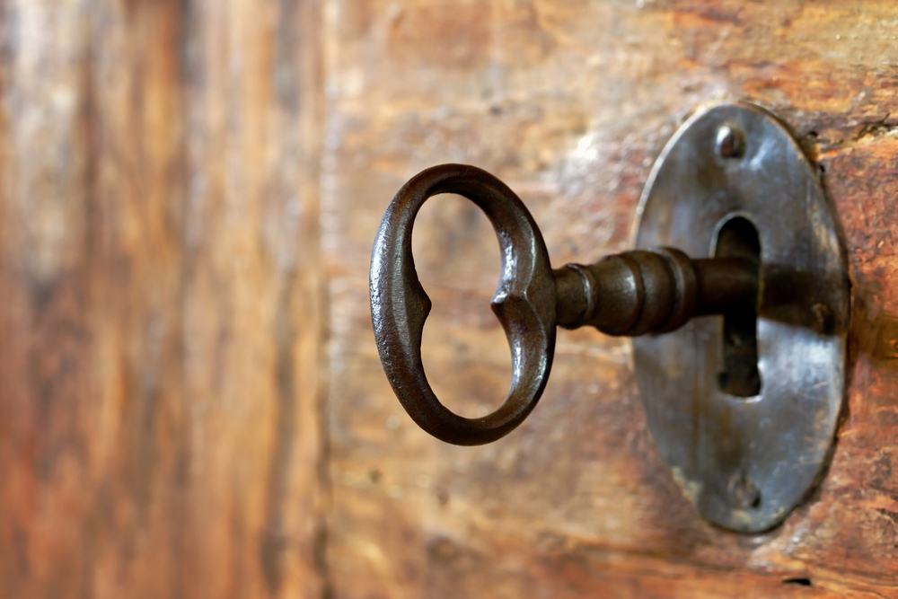 Closeup of an old keyhole with key on a wooden antique door