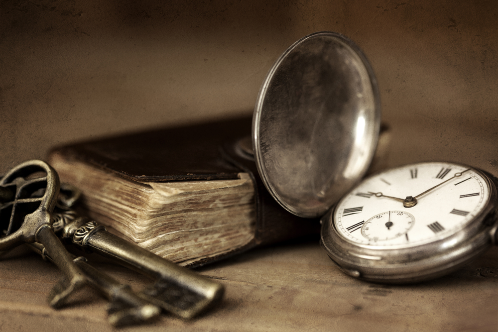 Vintage grunge still life with pocket watch, and old book and brass keys.