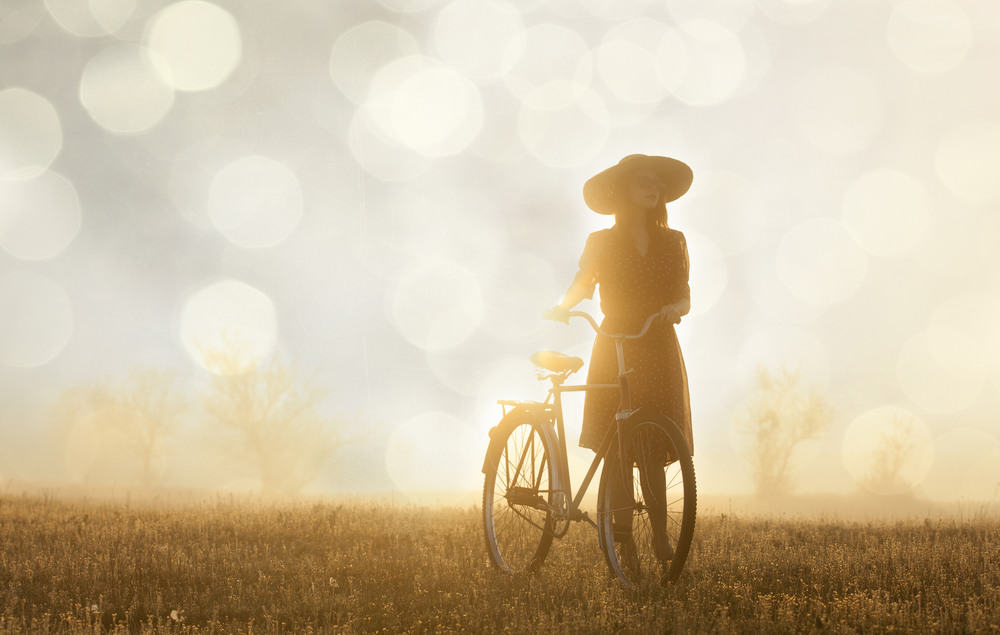 Girl and on a bike in the countryside in sunrise time